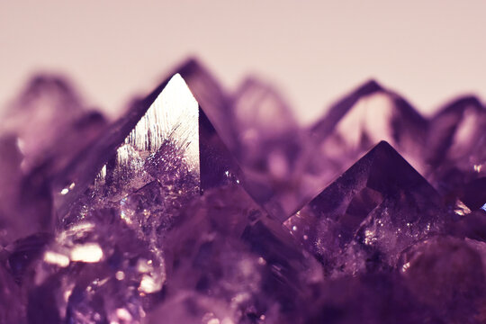 A close-up of a crystalline purple amethyst mineral stone. Selective focus. Macro photography of precious and semi-precious stones. The shiny surface of the precious crystal.