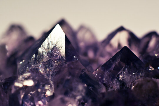 A close-up of a crystalline amethyst mineral stone. Selective focus. Macro photography of precious and semi-precious stones. The shiny surface of the precious crystal.