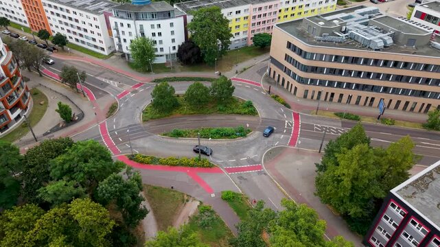 Aerial view of traffic around Pfalzer Platz near university and Nordpark in Magdeburg, Germany. Urban roads, tram tracks, cycle lanes, cars and modern buildings shape daily city transport scene