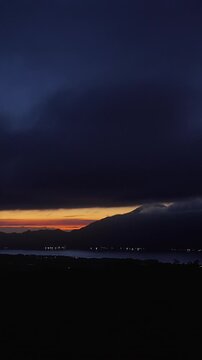 Vertical video. Dramatic Dawn Over Mount Abang and Lake Batur Beneath Massive Storm Clouds, Panoramic Volcanic Landscape With Glowing Horizon and Peaceful Highland Atmosphere