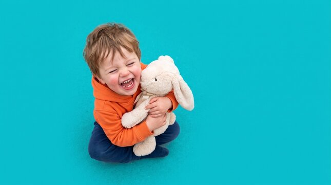 Toddler hugging stuffed bunny and smiling on a bright blue background  