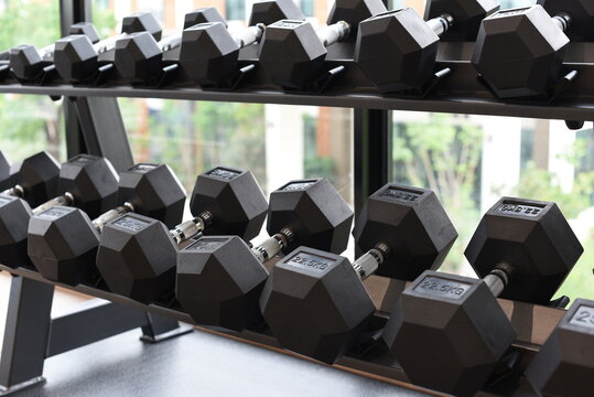 Black dumbbells on two tier storage rack in modern fitness gym