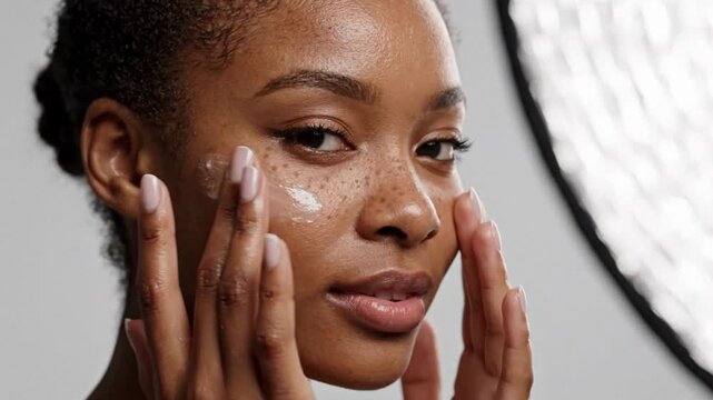 African female model applying facial cream gel freckled skin studio portrait cosmetic advertising