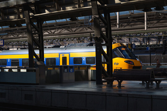 Amsterdam, Netherlands - August 12 2026: NS yellow and blue train waits at a historic Amsterdam railway station platform