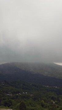 Vertical video. Volcanic Ridge Near Lake Batur Hidden Beneath Dense Clouds With Moody Light and Expansive Tropical Highland Scenery