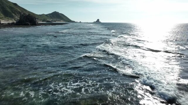 Aerial drone shot of 'Yahe-iwa', a massive sea rock and ancient castle site off the coast of Iheya Island, Okinawa.⁠