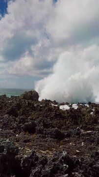 Vertical video. Powerful Waves Repeatedly Crashing Across a Rugged Rocky Coastline in Slow Motion