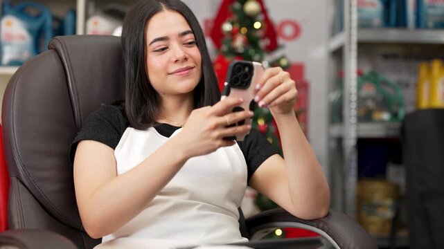 Young female employee sitting in an office chair and taking a selfie at a store during christmas