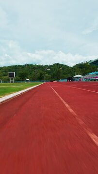 Vertical video. First Person FPV Drone Racing Along a Stadium Running Track at High Speed, Ultra Low Flight, Wide Angle Perspective, Dynamic Sports Action, Motion and Adrenaline