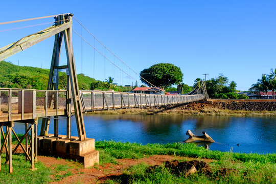 Historic Hanapepe Swinging Bridge spans the water in sunny Hanapepe, capturing daily life in Kauai, Hawaii
