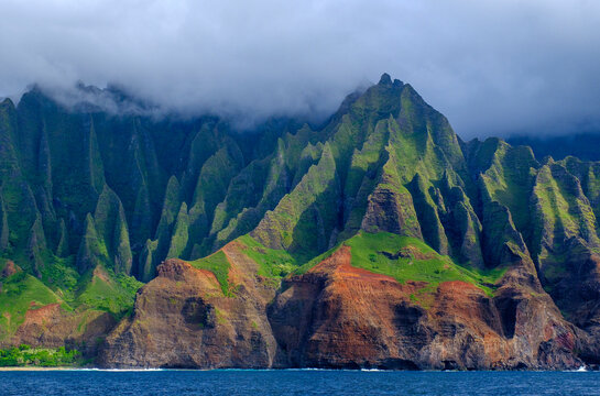 Dramatic sea cliffs rise from the ocean along the N Pali Coast on Kauai Island in a cloudy setting