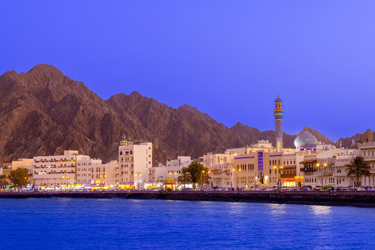 Mutrah Corniche illuminated by dusk light with mountains in the background in Muscat, Oman