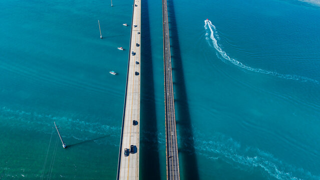 View of vehicles crossing 7 mile bridge along Highway Number 1 with boats in waters below in Florida Keys