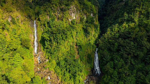 Waterfalls cascade down steep cliffs in lush greenery throughout the day at Morne Trois Pitons National Park in Dominica