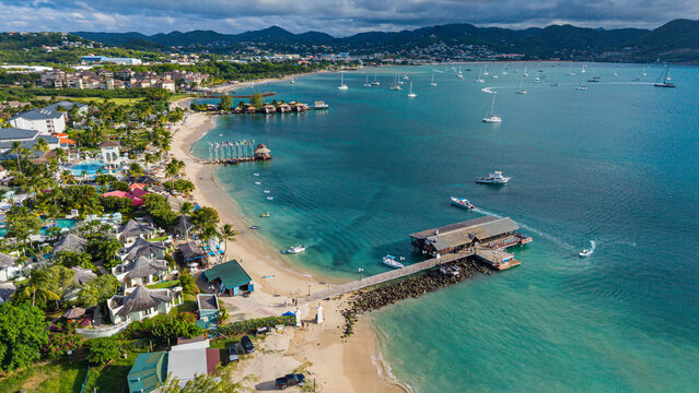Scenic view of Pigeon island beach with boats, structures, and green land at the coast in Saint Lucia