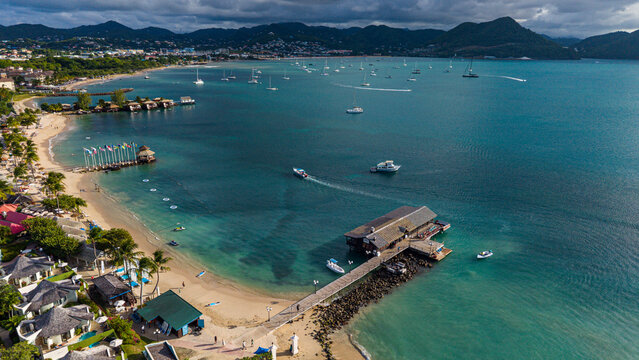 Aerial view of Pigeon island beach featuring boats, sandy shore, and clear water with distant hills in Saint Lucia