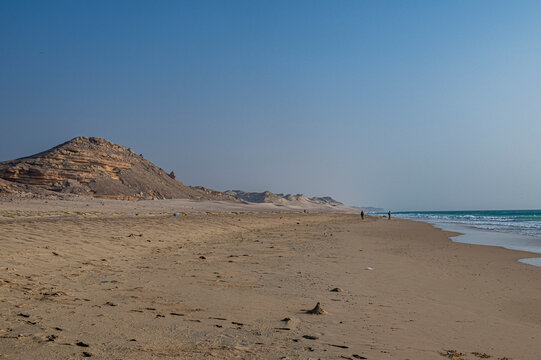 Long sandy beach with distant hills and two figures walking along the shoreline in Eyl, Puntland, Somalia