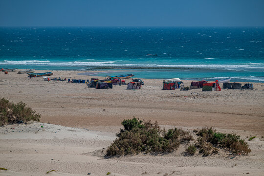 Fisher huts line the shore near the ocean with boats anchored in the distance off the coast of Eyl in Puntland, Somalia