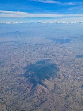 Aerial view of volcanic landscape in rift valley with terrain and clouds above in sunlight over Ethiopia