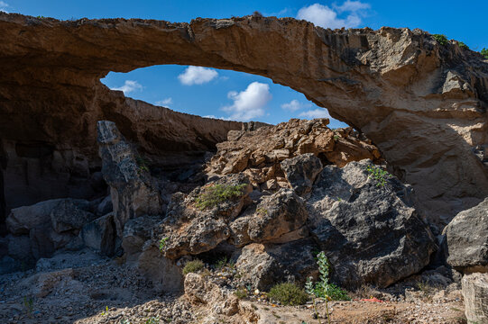 Stone arch structure spans a rocky area in a quarry with blue sky and clouds above in Jubaland, Somalia