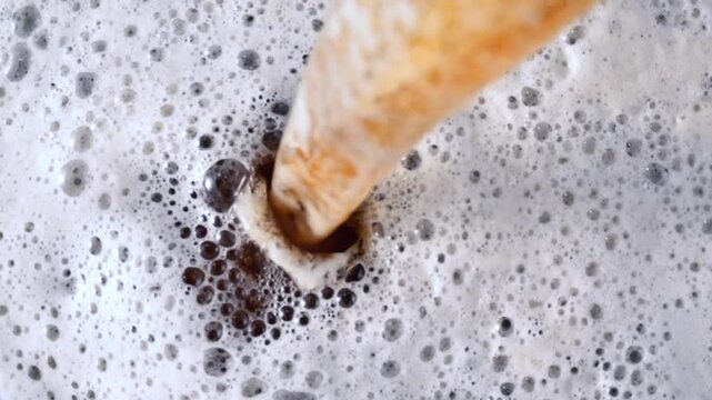 Top Down View of Amber Beer Pouring into Thick White Foam 