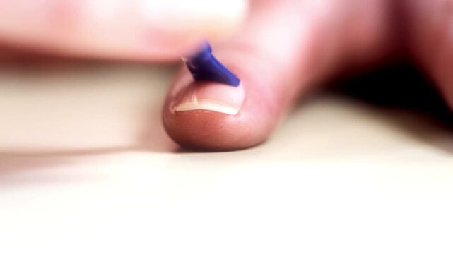 Blue nail polish applying cosmetic lacquer on long woman nails during professional manicure session in 4K Ultra HD footage.
