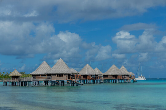 Overwater bungalows on Rangiroa Atoll in French Polynesia with clear lagoon water and a pier extending into the ocean