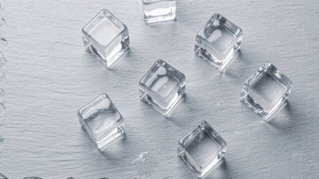 overhead view of crystal clear ice cubes on light grey slate surface minimalist airy commercial background for drink advertising