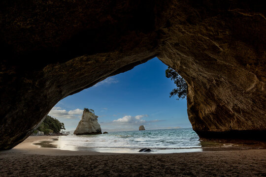 View through the tunnel at the sea cave entrance to Cathedral Cove with rock formations and water in the background