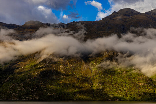 Doubtful Sound reveals mountains and clouds at sunset with water reflecting the landscape near Fjordland National Park