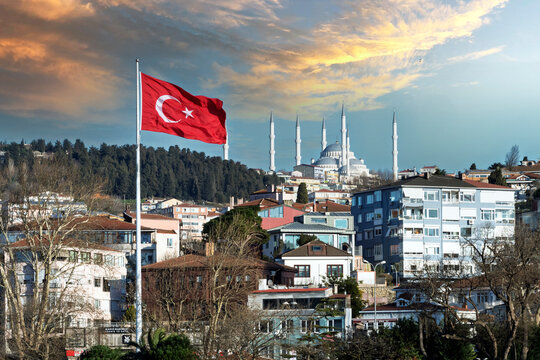 View of Camlica mosque with Turkish flag in foreground in Istanbul at sunset