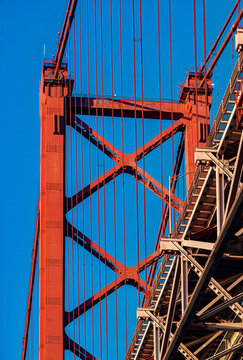 Low perspective view of 25 April Bridge with cables and structure over Tagus River at midday in Lisbon Portugal
