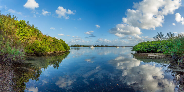 Water channel lined with greenery and clouds reflecting in the water near the International Airport in Bermuda