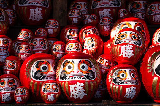 Traditional red Daruma dolls densely arranged on a wooden altar at a temple in Japan