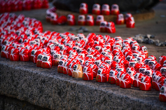 Miniature red Daruma dolls at Katsuo-ji Temple represent perseverance and personal wishes in Japan