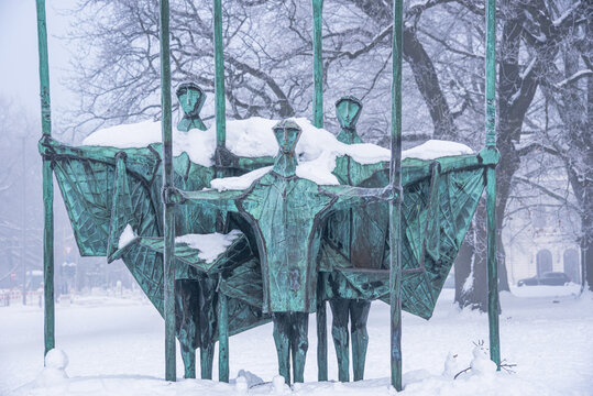Close-up view of bronze figures at Die Auswanderer monument during snowfall in Hamburg, Germany, depicting hopeful emigrants leaving for new lives