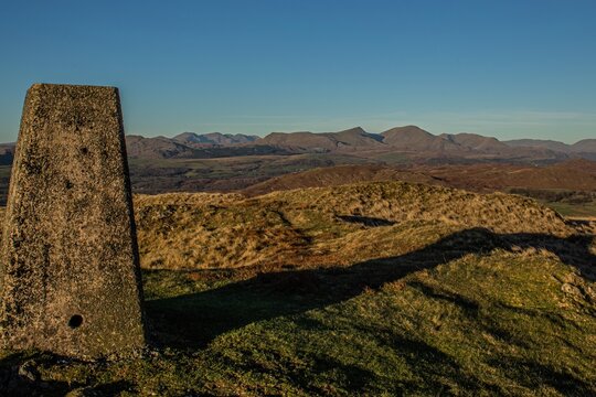 View of distant hills and a marker on Kirkby Moor in South Cumbria during clear weather in late afternoon light