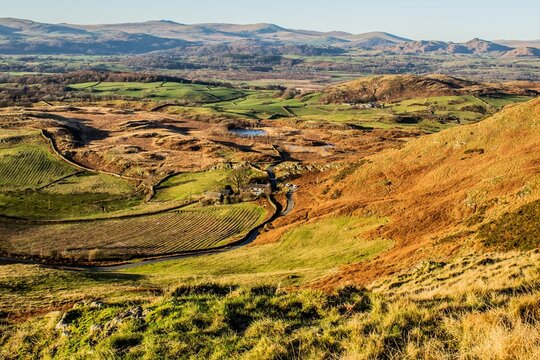 View of Kirkby Moor and valley in South Cumbria with distant hills and fields under clear sky in winter light
