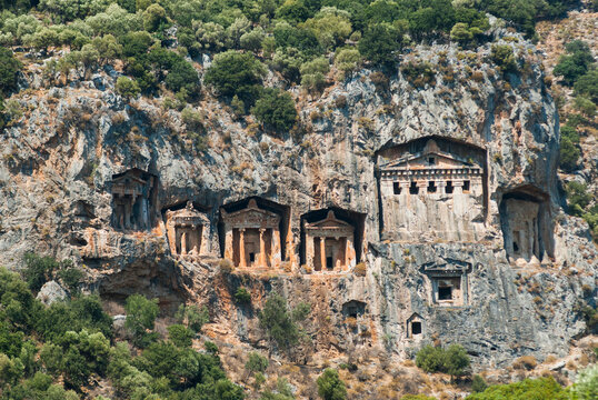 Rock-cut tombs of ancient Lycia carved into cliffs near a river in Turkey
