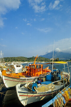 Fishing boats at a harbour in Palaia Epidavros with mountains and clouds in the background in Southern Europe