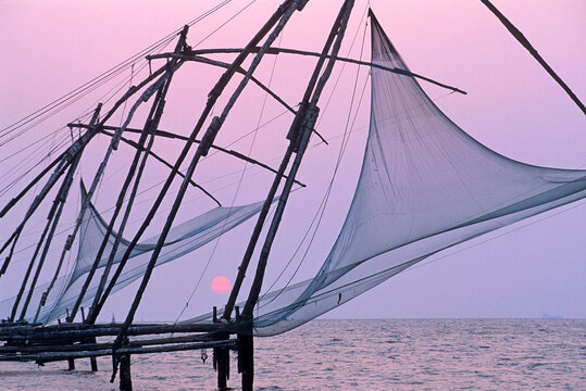 Fishing square nets against the sunset in the backwaters of Kerala highlight the local fishing culture