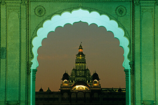 View of illuminated building through arch at dusk in Mysore in Karnataka