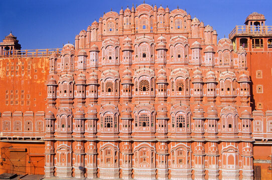Hawa Mahal features intricate window designs and historical architecture in sunlight above the streets of Jaipur