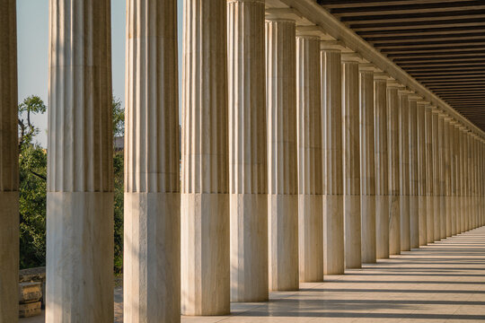 Marble colonnade with repeating Doric columns and geometric shadows in a neoclassical structure in Athens, Greece.