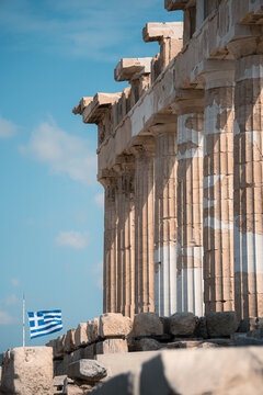 Doric columns of the Parthenon on the Acropolis with the Greek flag flying in the background, Athens, Greece.
