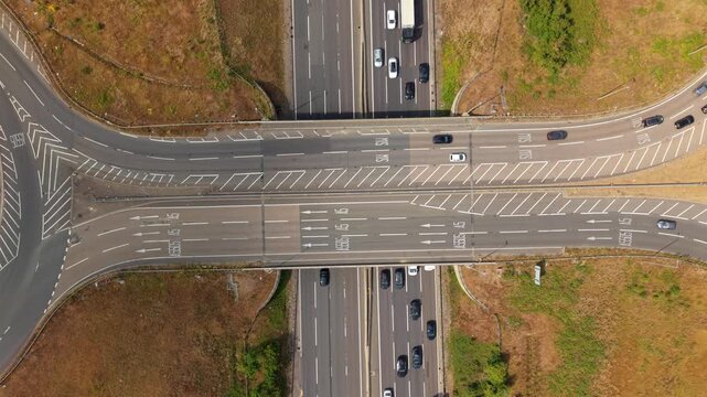 Top-down aerial drone view of busy M1 motorway junction bridges and traffic near Luton, UK