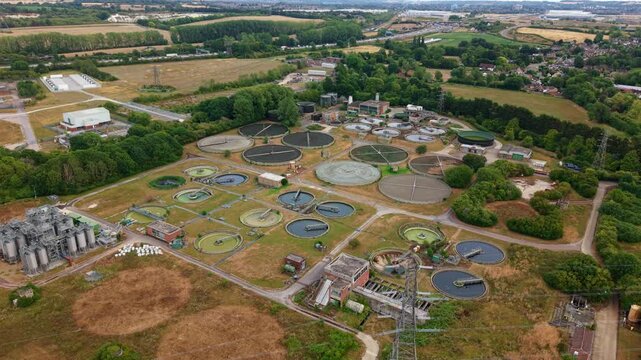 Aerial view of a large municipal wastewater sewage treatment plant with circular clarifiers and sedimentation tanks in Luton, Bedfordshire, England, UK