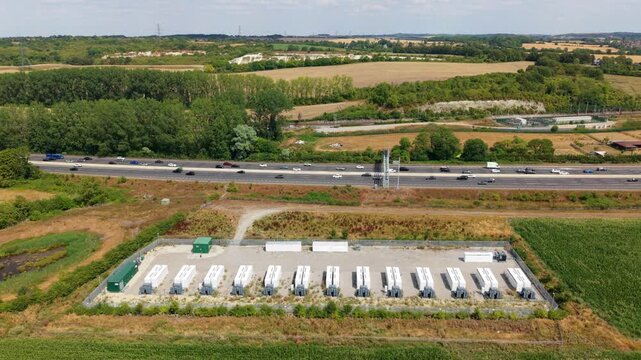 Aerial view of grid scale battery energy storage park and busy M1 motorway traffic near Luton UK