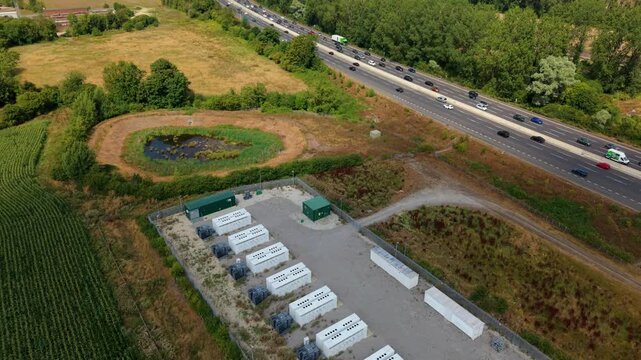 Aerial view of grid scale battery energy storage park and busy M1 motorway traffic near Luton UK