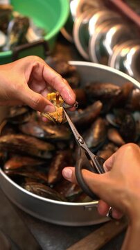 Cooking Thai stir-fried mussels with sweet basil (Hoi Maelang Phoo Phad Ho Ra Pha). Saut&eacute;ing chili and garlic, seasoning sauce, tossing with steamed mussels and basil.